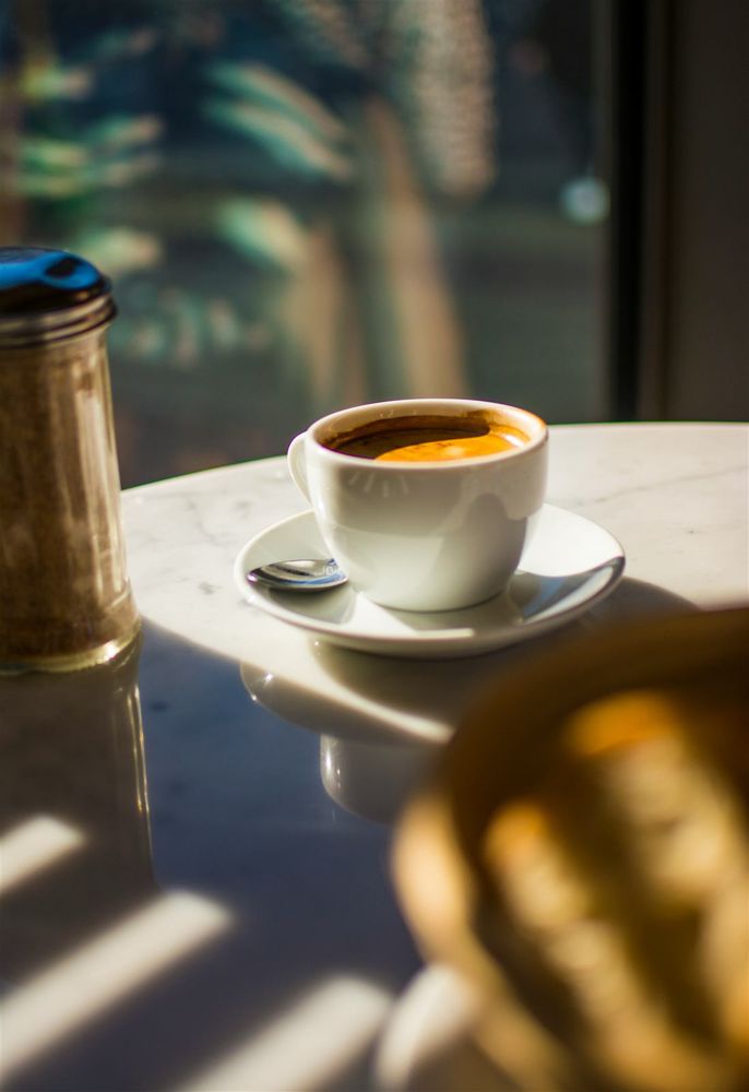 Coffee and a cinnamon pastry on a sunlit table